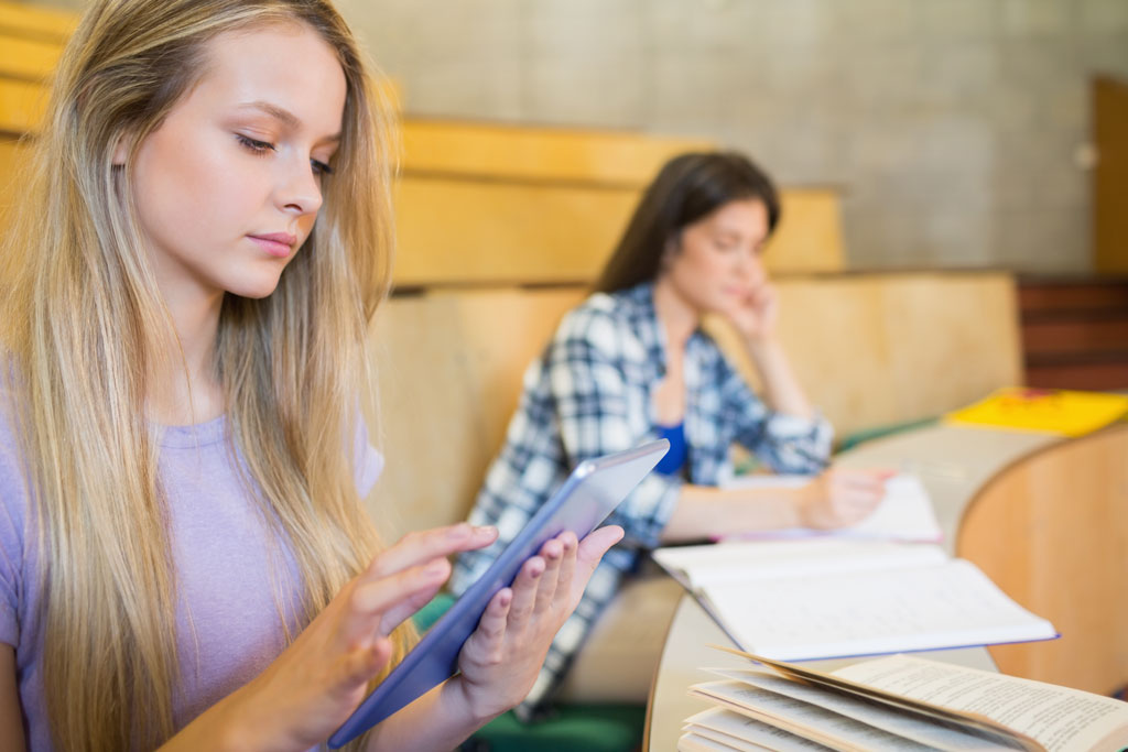 Junge Frau mit iPad in Uni Vorlesung